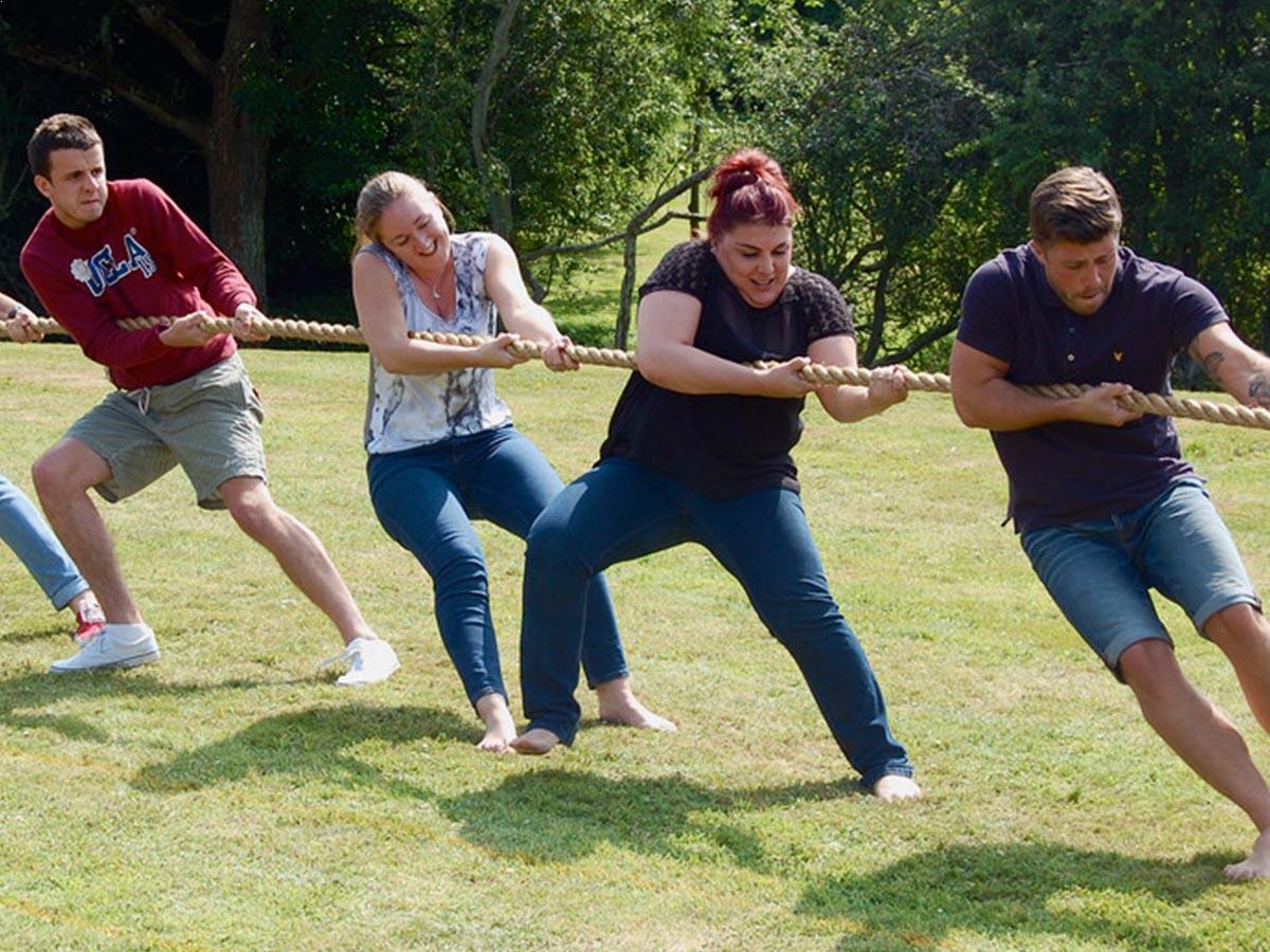 Men and women playing tug of war, one side of the rope.